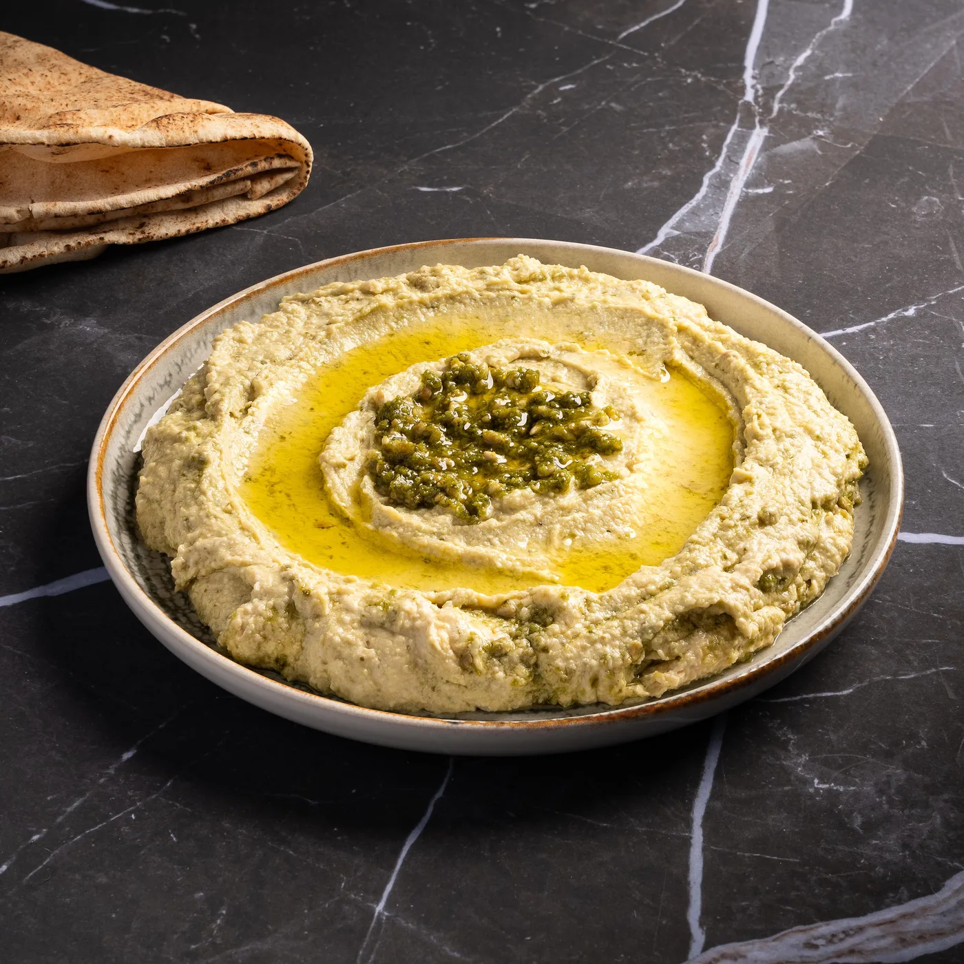 Hommos maison, purée de pois chiches au tahini nappée d'huile d'olive et d'herbes fraîches